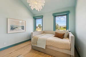 Bedroom featuring lofted ceiling, wood-type flooring, and a chandelier