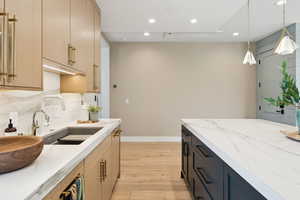 Kitchen with light stone countertops, pendant lighting, light brown cabinets, recessed lighting, and light wood-style floors