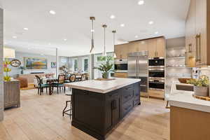 Kitchen with a breakfast bar area, stainless steel appliances, decorative light fixtures, light wood-style flooring, and recessed lighting