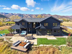 Rear view of property featuring a patio area, a fire pit, board and batten siding, a mountain view, and a yard