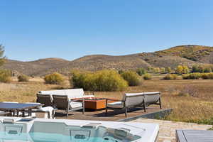 View of pool featuring a mountain view, a fire pit, a patio area, and a hot tub