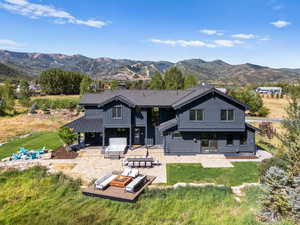 Rear view of house featuring a patio, a lawn, a mountain view, and an outdoor fire pit