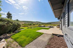 View of grassy yard featuring a patio and a mountain view