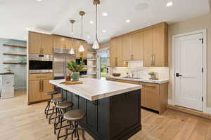 Kitchen with open shelves, hanging light fixtures, light brown cabinetry, a kitchen island, and recessed lighting