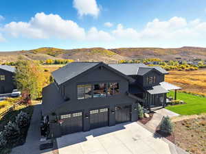 Modern farmhouse style home featuring an attached garage, concrete driveway, a mountain view, and a metal roof