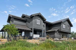 Back of property with board and batten siding, a patio, and a standing seam roof