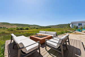 Deck with an outdoor living space with a fire pit, a mountain view, and a patio