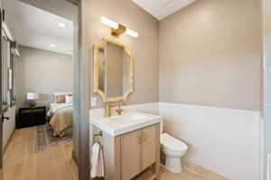 Ensuite bathroom featuring vanity, recessed lighting, tile walls, and wainscoting