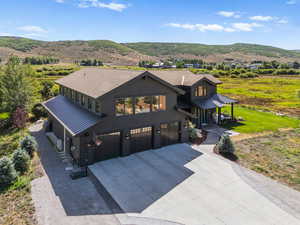 View of front of house with driveway, a garage, a metal roof, and a mountain view