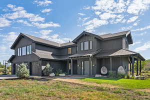 View of front of property with a metal roof, a garage, a front lawn, board and batten siding, and concrete driveway