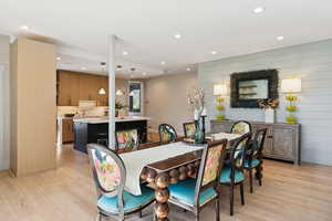 Dining space featuring light wood finished floors, recessed lighting, and wooden walls