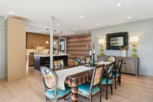 Dining space with light wood finished floors, recessed lighting, and wooden walls