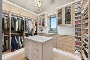 Spacious closet with light wood-style flooring and a chandelier