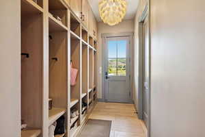 Mudroom with light wood finished floors and a chandelier