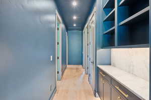 Corridor with light wood-style flooring and recessed lighting