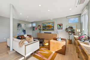 Living area featuring recessed lighting, light wood-style flooring, and wooden walls