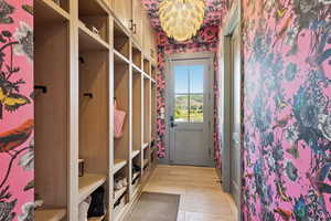 Mudroom featuring light wood finished floors and wallpapered walls
