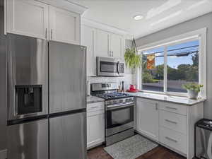 Kitchen featuring stainless steel appliances, white cabinets, light stone countertops, recessed lighting, and decorative backsplash