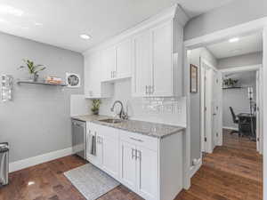 Kitchen with dark wood finished floors, white cabinets, light stone counters, recessed lighting, and a textured ceiling