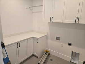 Washroom with hookup for an electric dryer, cabinet space, and washer hookup