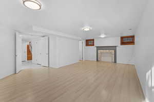 Unfurnished living room with stairway, light wood-type flooring, and a fireplace