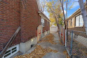 View of side of home with brick siding, an outdoor structure, and a garage