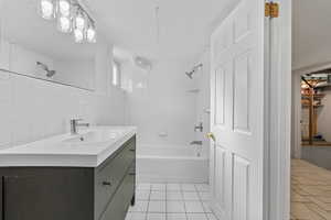Full bathroom with bathing tub / shower combination, vanity, light tile patterned floors, tile walls, and backsplash