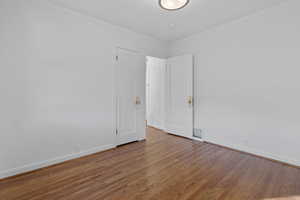 Empty room featuring wood finished floors and crown molding