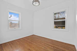 Unfurnished room with wood finished floors, plenty of natural light, and crown molding