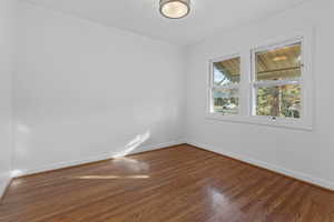 Empty room featuring wood finished floors and crown molding