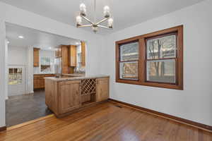 Kitchen featuring dark wood-style flooring, decorative light fixtures, light stone counters, a chandelier, and recessed lighting