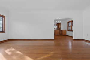 Empty room featuring light wood finished floors, arched walkways, and a chandelier