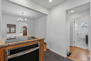 Kitchen featuring stainless steel oven, light stone countertops, dark tile patterned flooring, black electric cooktop, and recessed lighting