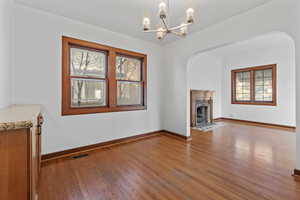 Unfurnished living room featuring wood-type flooring, a fireplace, and a chandelier