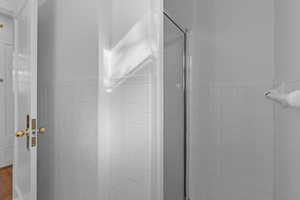 Bathroom featuring tile walls, a stall shower, and a wainscoted wall