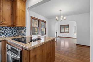 Kitchen with brown cabinets, dark wood-style flooring, and backsplash