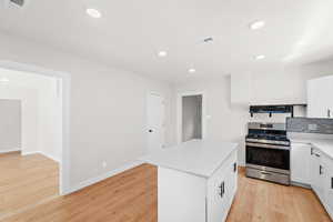 Kitchen featuring brand new white cabinets, quartz countertops, large island with bar for seating, laminate flooring and stainless steel appliances. Kitchen also features a large sized pantry
