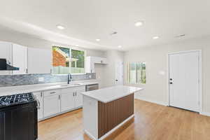 Kitchen featuring brand new white cabinets, quartz countertops, large island with bar for seating, laminate flooring and stainless steel appliances. Kitchen also features a large sized pantry