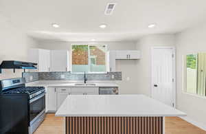 Kitchen featuring brand new white cabinets, quartz countertops, large island with bar for seating, laminate flooring and stainless steel appliances. Kitchen also features a large sized pantry