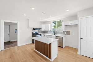 Kitchen featuring brand new white cabinets, quartz countertops, large island with bar for seating, laminate flooring and stainless steel appliances. Kitchen also features a large sized pantry