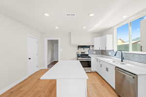 Kitchen featuring brand new white cabinets, quartz countertops, large island with bar for seating, laminate flooring and stainless steel appliances. Kitchen also features a large sized pantry