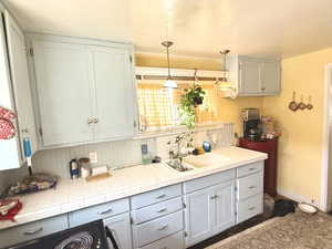 Kitchen with black range with electric cooktop, pendant lighting, and tasteful backsplash