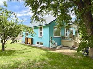 Back of house with a metal roof, a lawn, and stucco siding