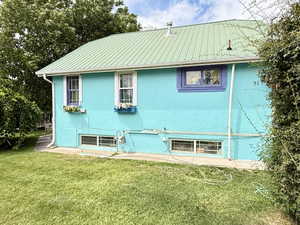 Rear view of house featuring stucco siding and a lawn
