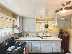 Kitchen with electric range, tile countertops, and decorative light fixtures