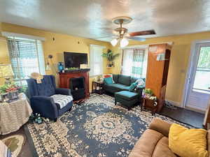 Living area featuring a textured ceiling, wood finished floors, and a ceiling fan