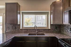 Kitchen featuring dark brown cabinets, decorative backsplash, and dark stone countertops