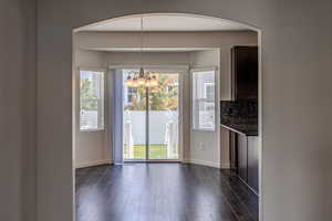 Unfurnished dining area with dark wood finished floors, a chandelier, and arched walkways