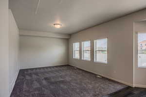 Empty room with a textured ceiling and baseboards