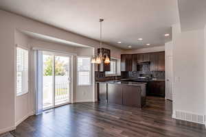 Kitchen featuring a chandelier, dark countertops, dark brown cabinets, tasteful backsplash, and a peninsula